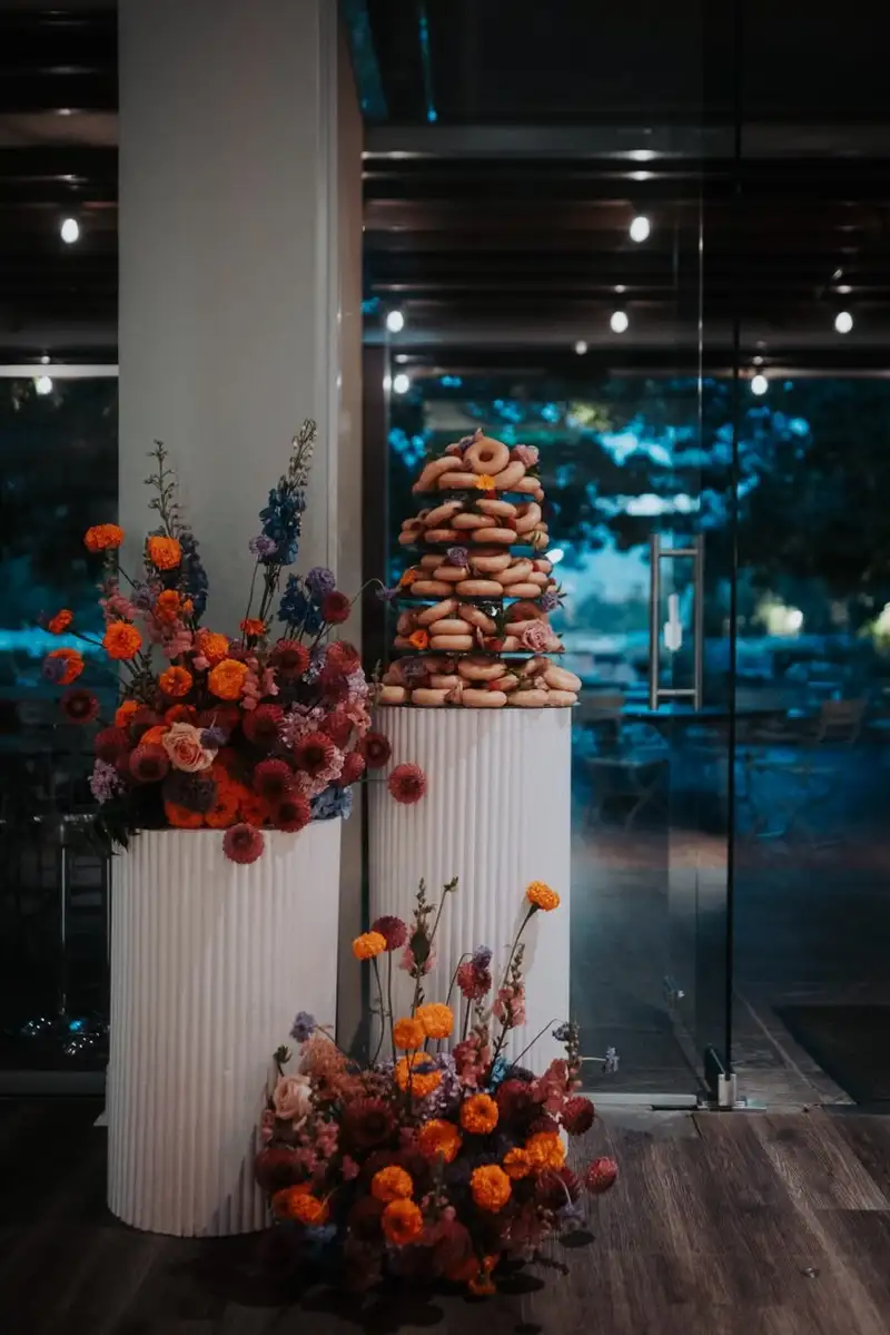 Croquembouche tower on a fluted plinth flanked by orange and red florals