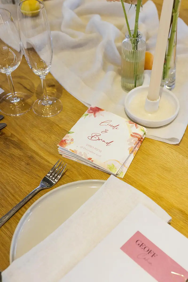 Printed menu and place card on a wooden table with green tapered candles