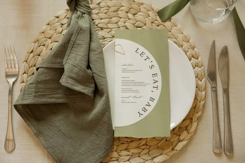 Printed menu on a woven placemat with an olive linen napkin and cutlery