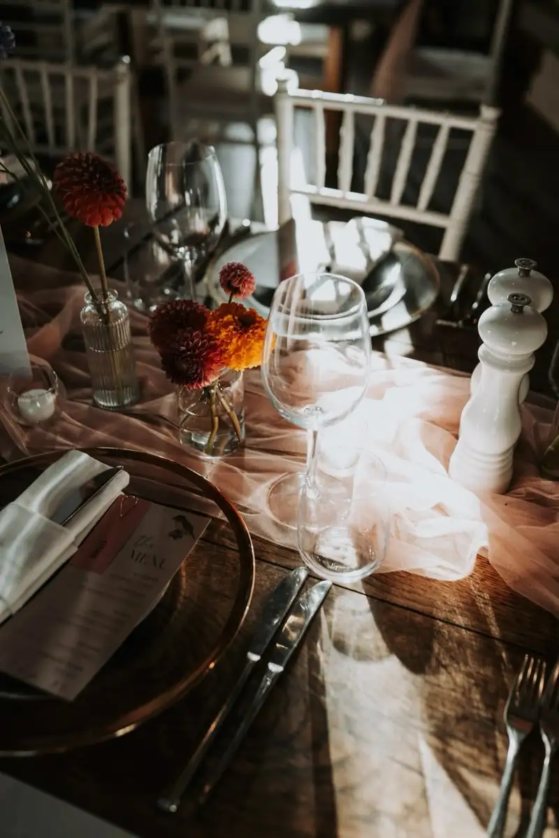 Long table set with orange dahlias, glassware and chiavari chairs