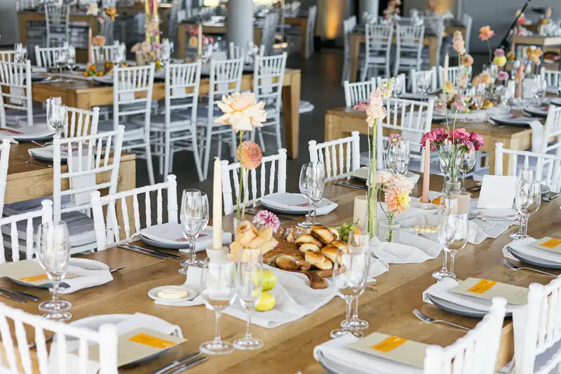 Long wooden reception tables set with florals, candles and printed menus
