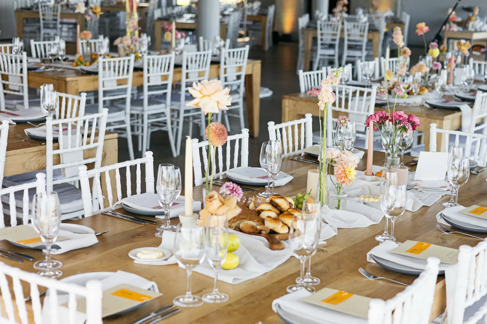 Long wooden reception tables set with florals, candles and printed menus