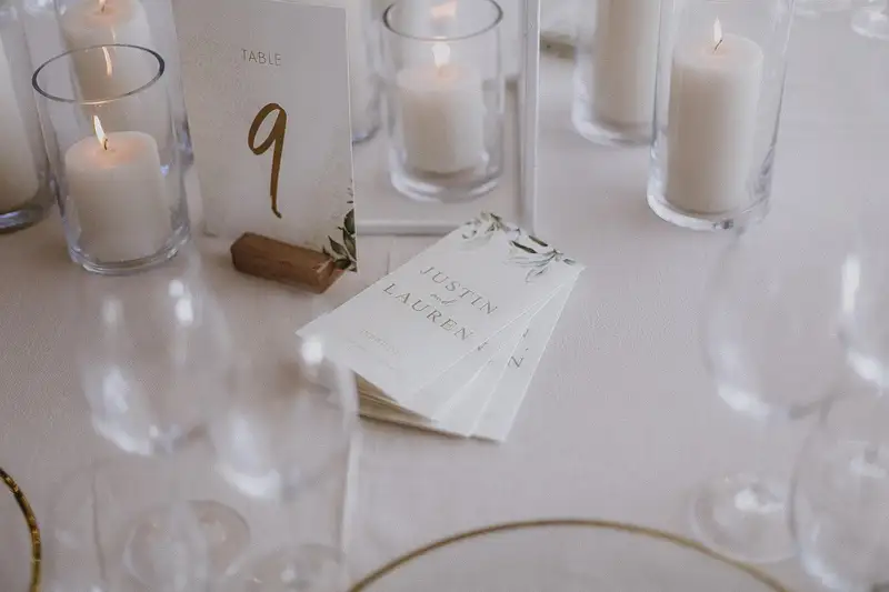 Table number nine beside stacked menus and pillar candles on a white cloth