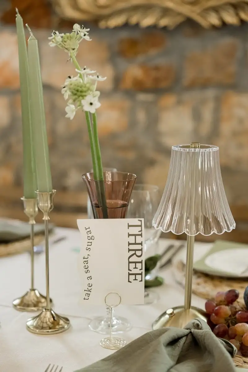 Table number three propped between green tapered candles and a glass lamp