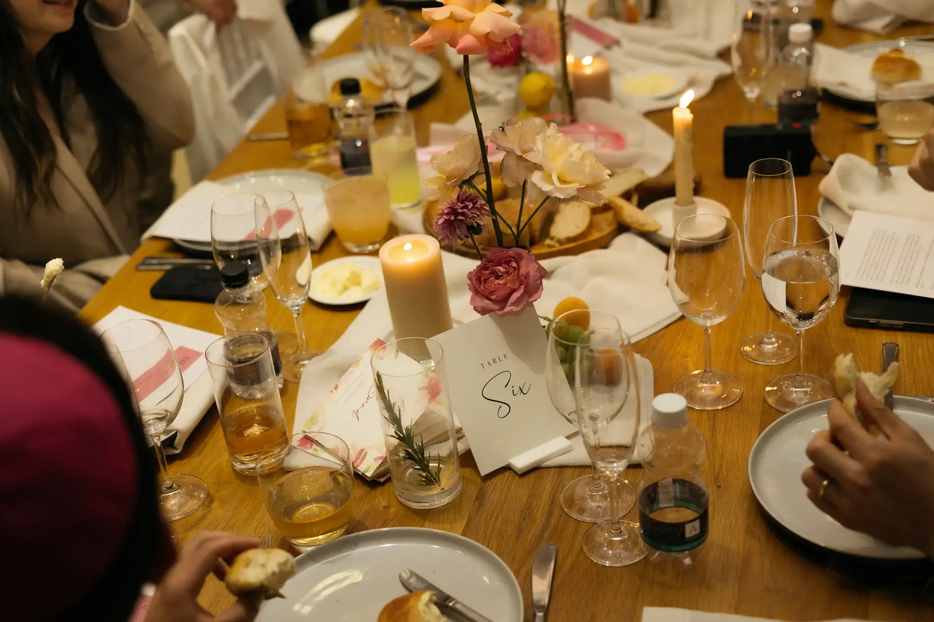 Candlelit dinner table with roses, printed menus and a table number card